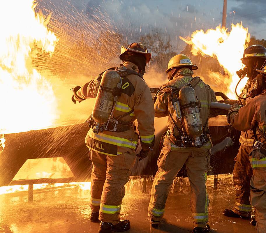 Firefighters up close putting out a fire.