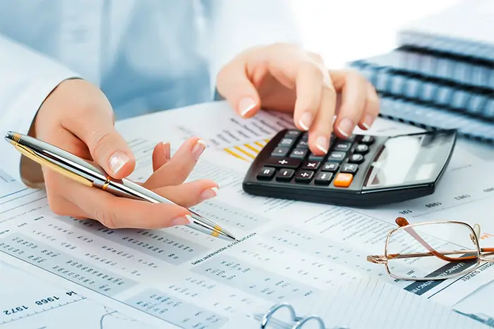 Close up of hand using calculator at desk.