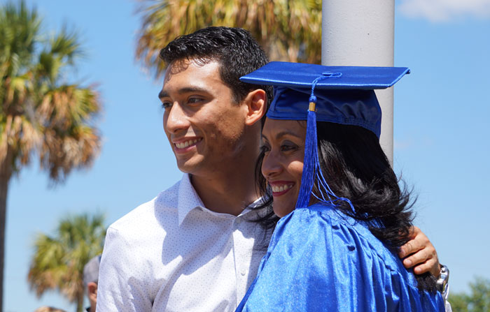 Graduate outside ceremony taking photo with family members