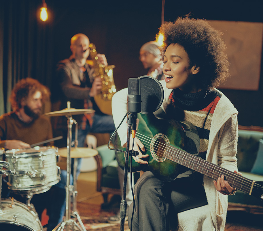 Young female playing guitar and singing in a band.