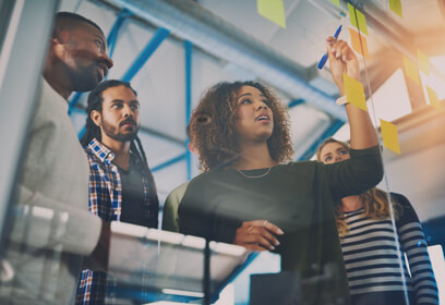Marketing team planning with sticky notes on clear whiteboard