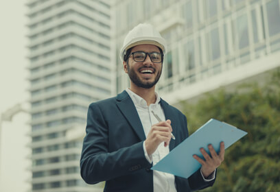 Business man outside city building with hardhat and clipboard
