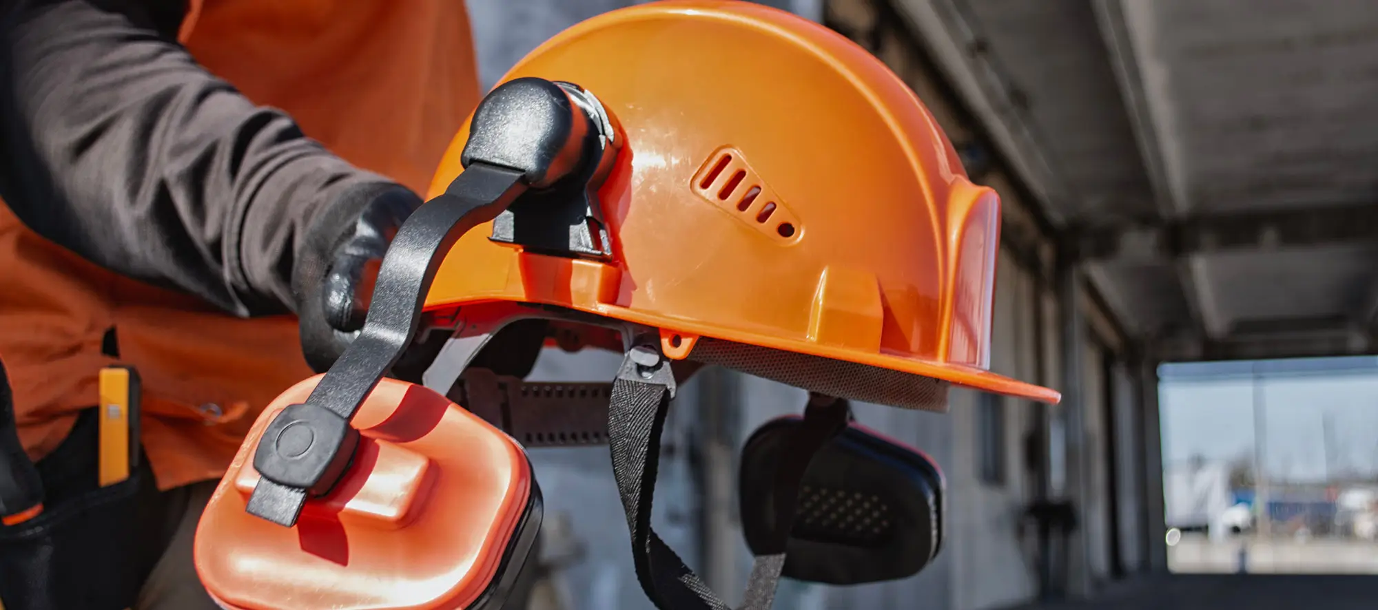 Close up of professional protective hard hat and ear defenders on industrial site.