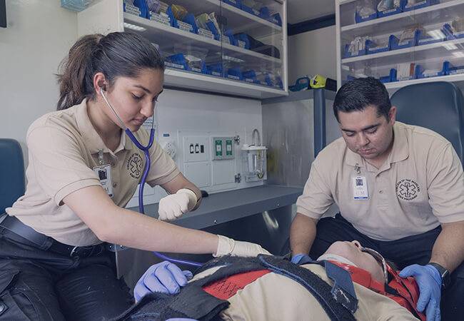 Two EMT's caring for a person in the back of an ambulance