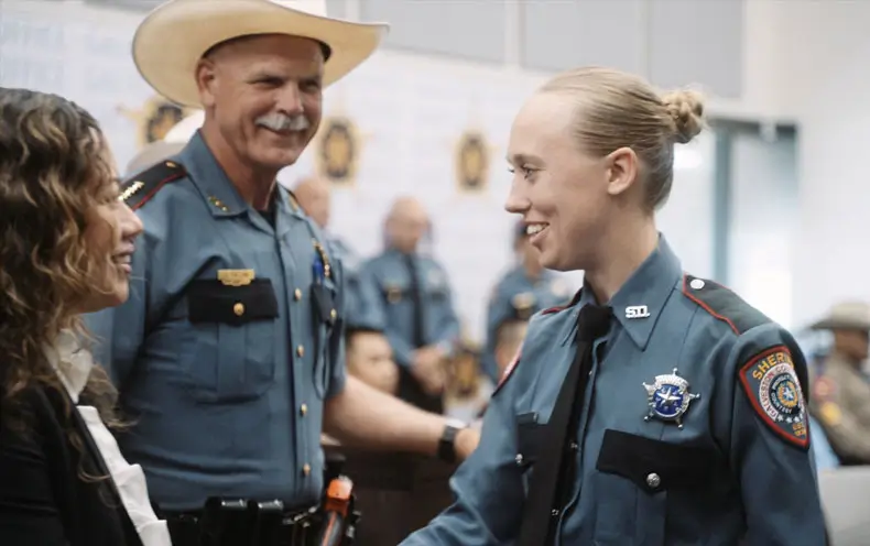 Female officer graduating and shaking hands.