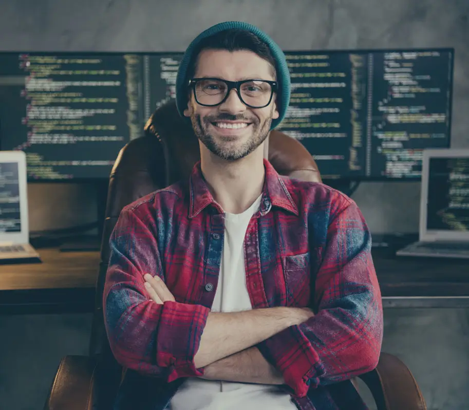 Photo of good mood happy coder dressed hat glasses smiling arms folded indoors workplace workstation loft. Pharmacy Technician