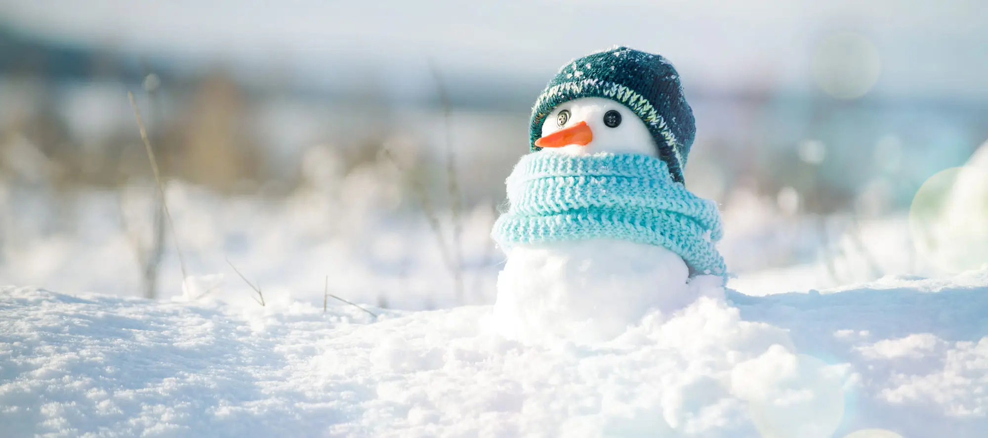 Little snowman in a cap and a scarf on snow in the winter.