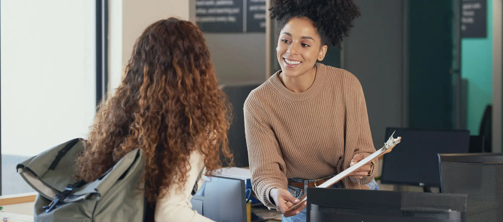Young woman checks in at front desk, reception, hotel, college library admission.
