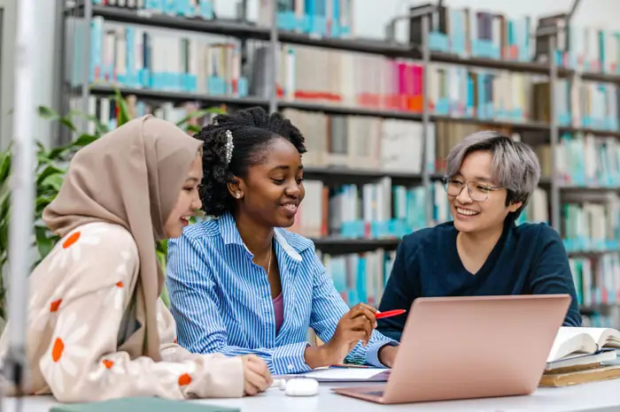 Multiethnic group of students sitting in a library and studying together