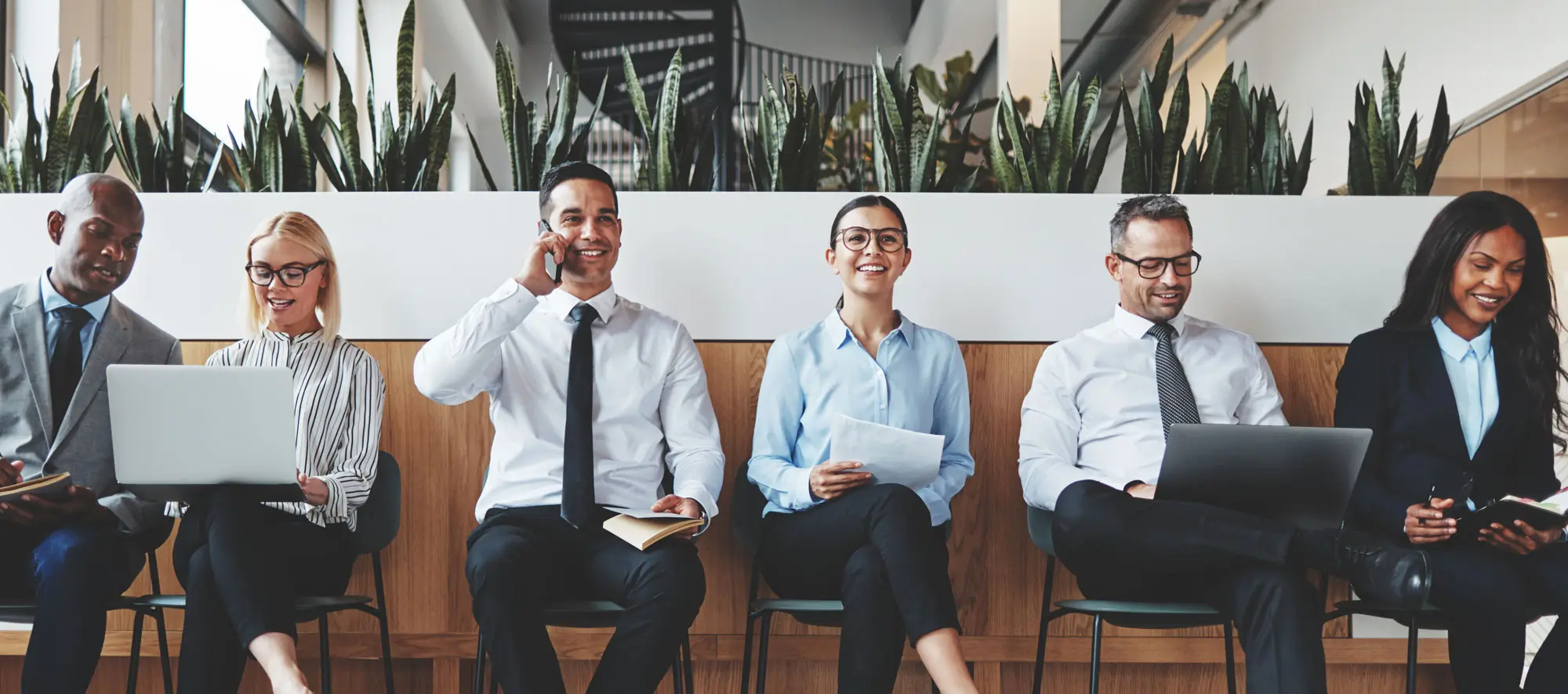 Group of businesspeople smiling while waiting together in an office.
