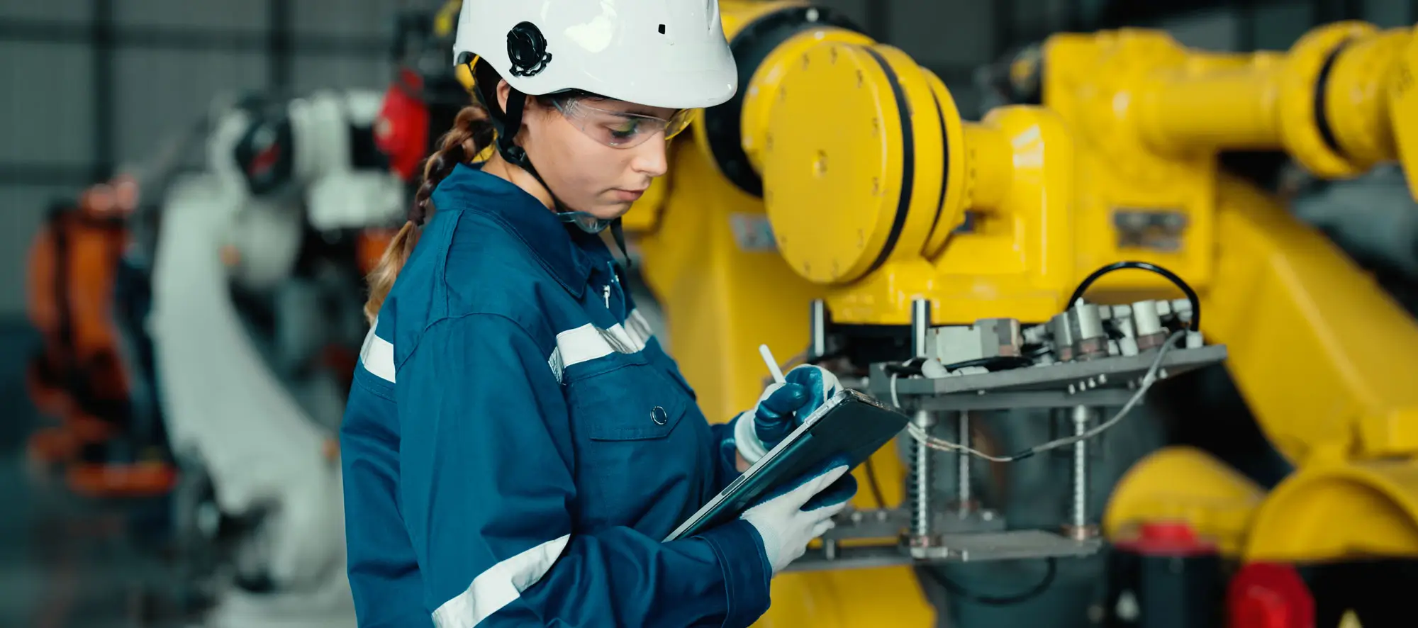 A female industrial worker with responsibility for quality checking machines in the factory.