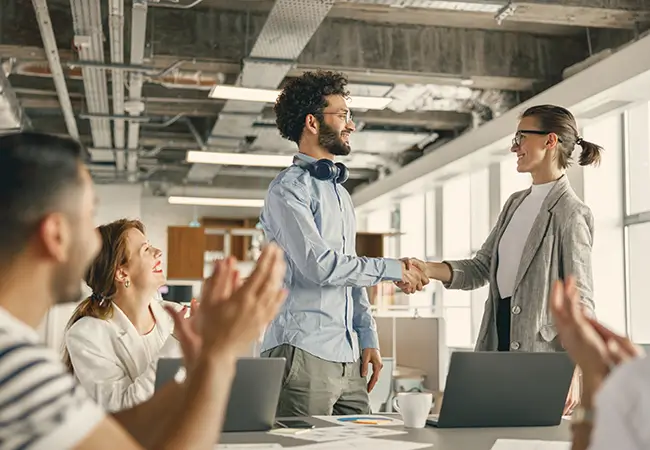 Young man shaking the hand of a female executive at interview.