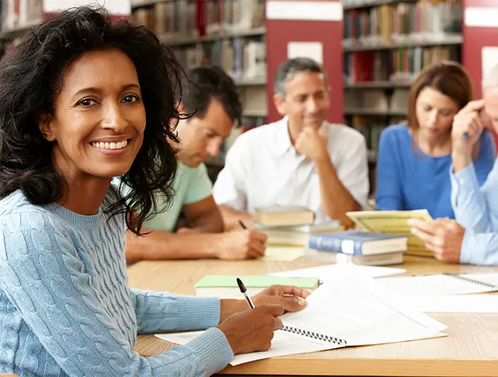 Senior citizen studying at a table with fellow students. 