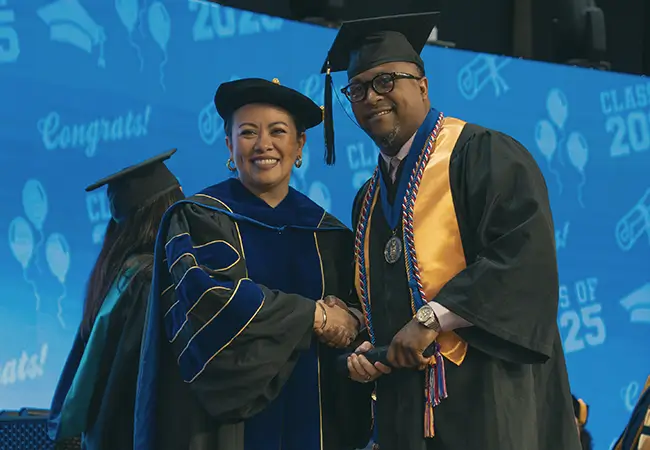 Graduate on stage with President Dr. Brewer