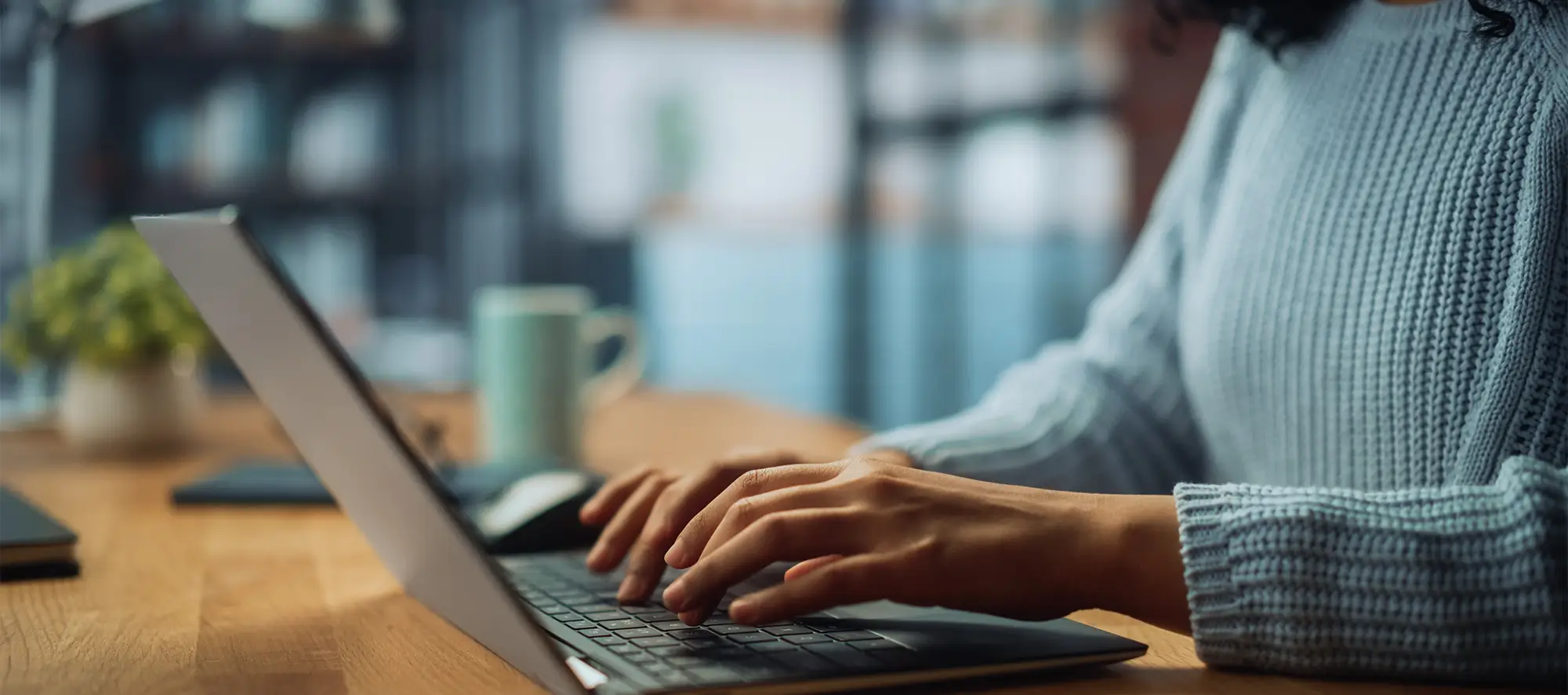 Close Up on Hands of a Female Working on Laptop Computer at Cozy Home Living Room while Sitting at a Table.