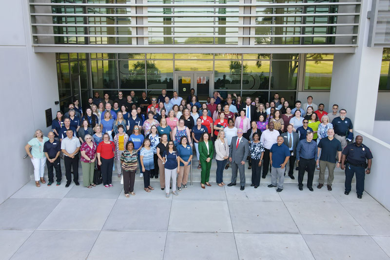 COM employee group photo outside ICB Building