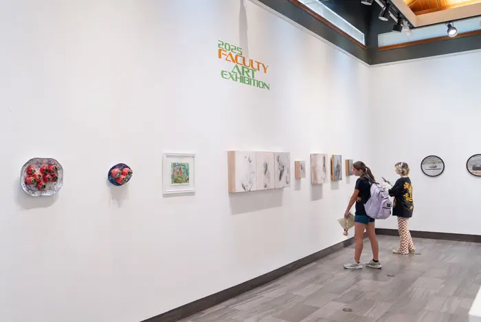 Two students walking through the art gallery looking at paintings.