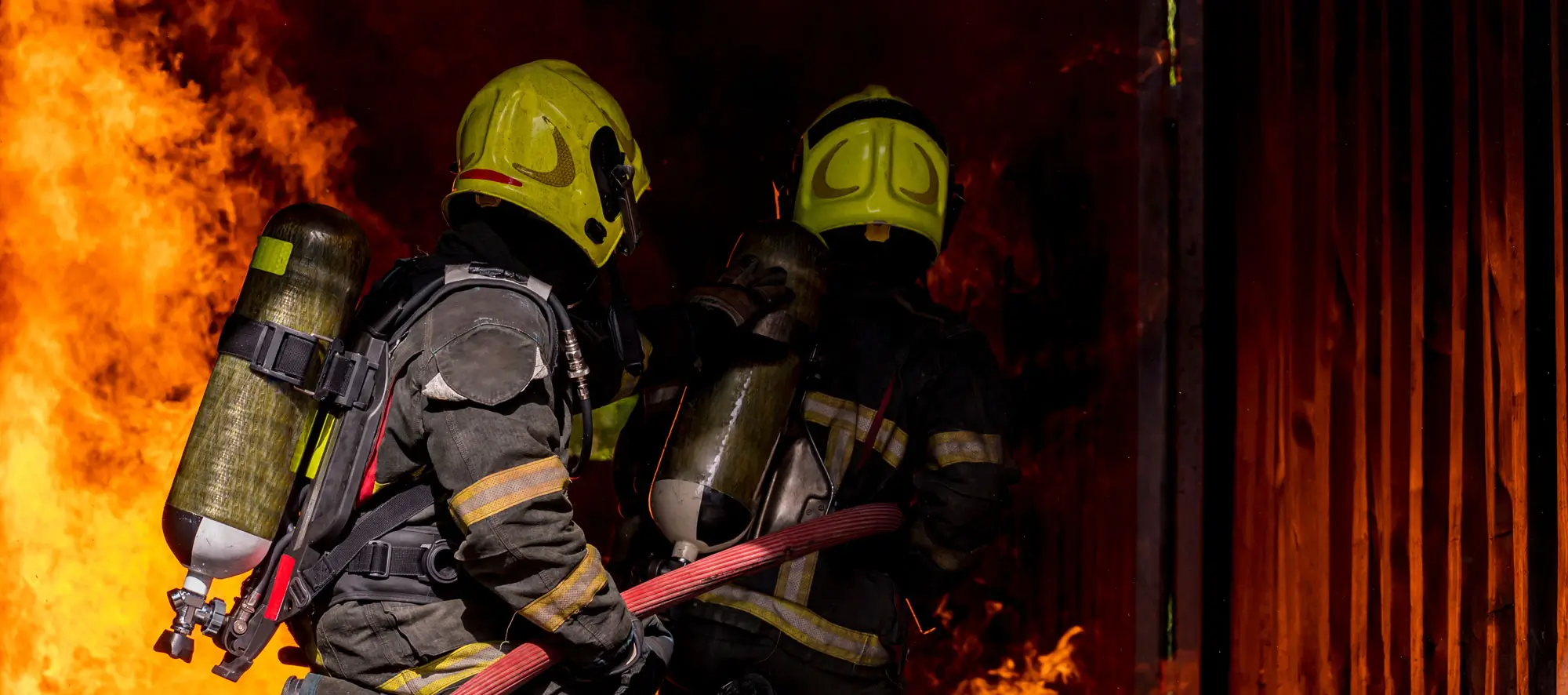 firefighters wearing fire fighter suit for safety and using twirl water extinguisher for fighting a fire.