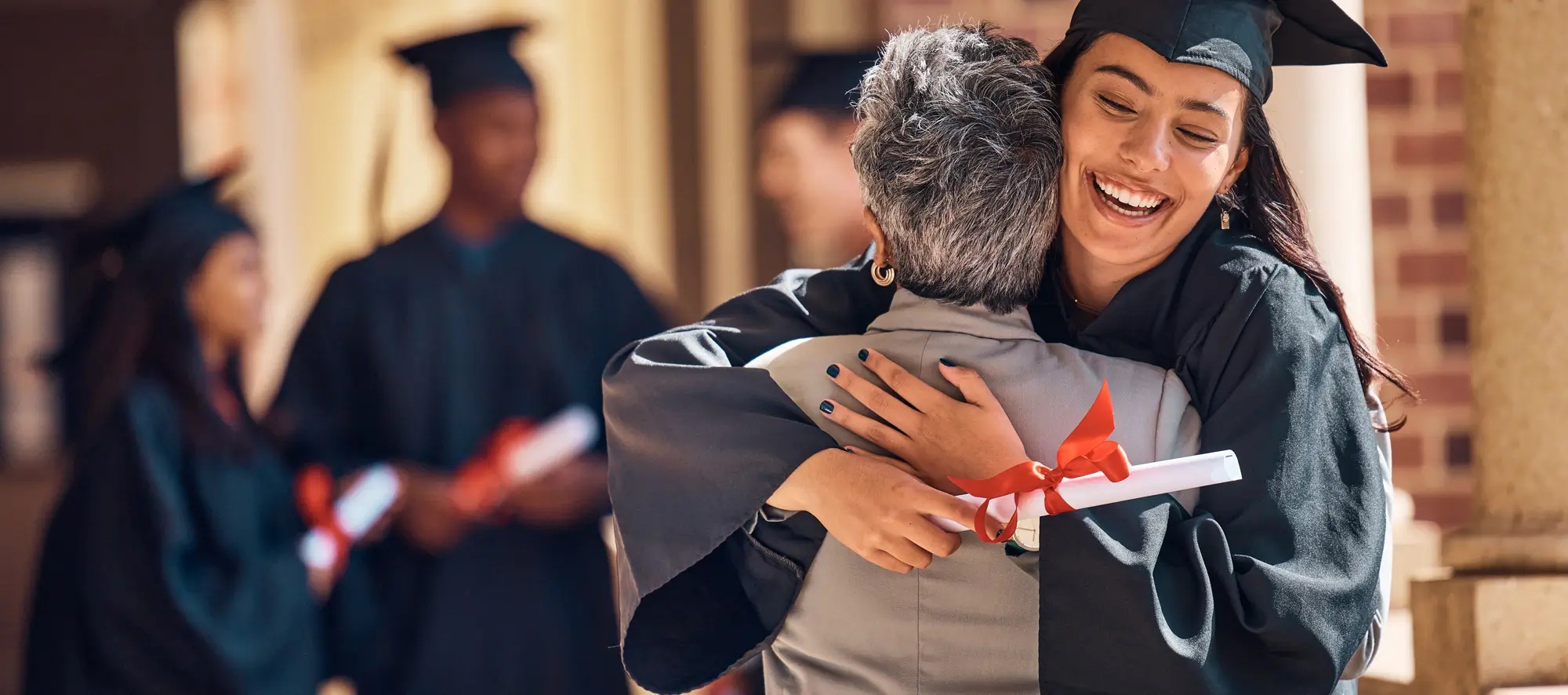 Female grad outside ceremony hugging a family member