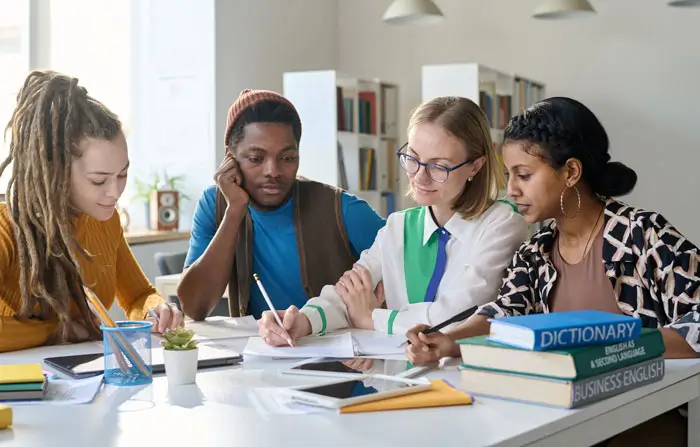 Female instructor at large table with students gathered around watching her writing demonstration.