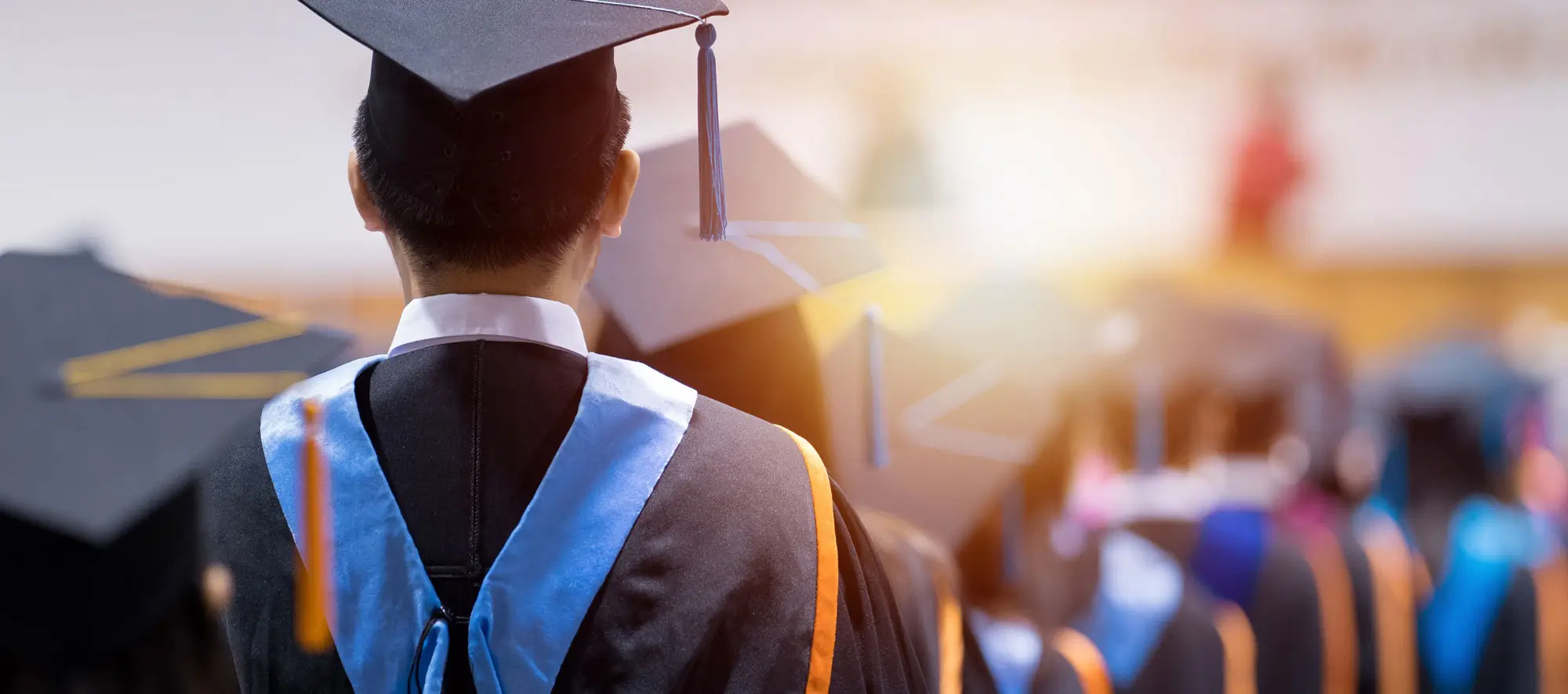 Rear view of university graduates wearing graduation gown and cap in the commencement day